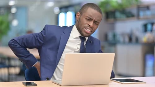 Tired African Businessman with Laptop Having Back Pain in Office