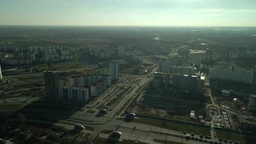 Flight over city blocks. Multi-storey buildings and construction site.