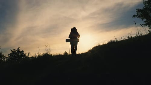 Back View Silhouette of Walking Man with Backpack on the Mountain