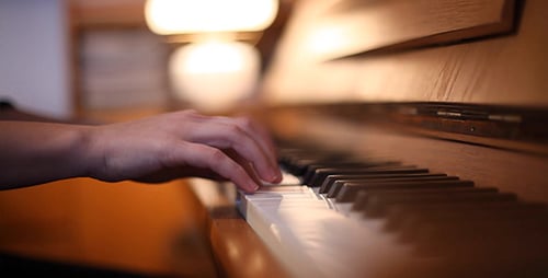 Hands Playing Piano Keyboard in Warm Light