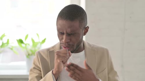 Young Adult Coughing and Holding Chest Indoors