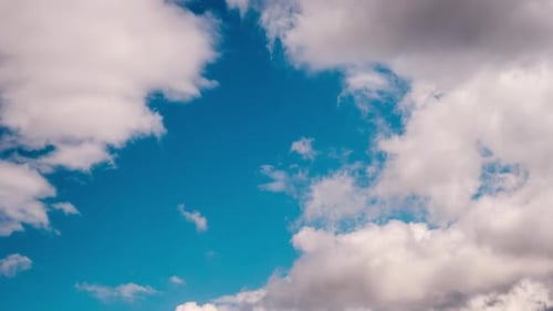 Fluffy White Clouds Drifting Across Blue Sky
