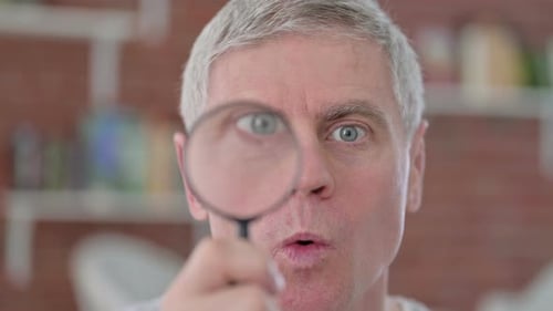 Man Examines with Magnifying Glass, Looks Surprised