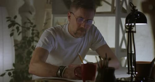 Man Drawing Sketches at Table in Studio