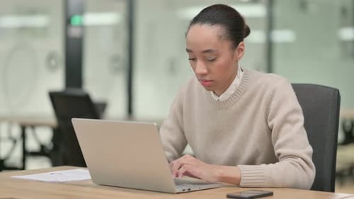Young Adult Working on Laptop in Modern Office