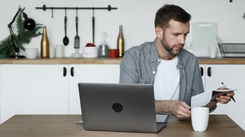 Man working on laptop in bright kitchen