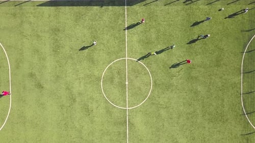 Top down aerial view of green football sports field and players playing football.