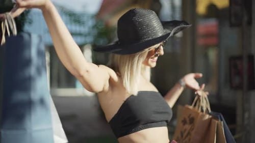 Stylish Young Woman in Sunglasses Hat and Pants in a Strip is Fashionably Dressed Goes Shopping at