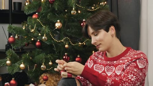 Woman Tying Red Ribbon on Christmas Gift