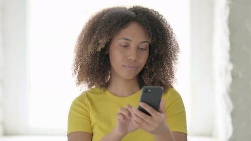 Young Woman Using Smartphone in Bright Indoor Setting