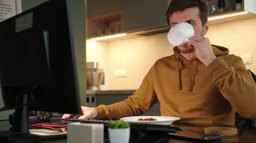 Man Works Remotely at Home Office and Drinks Coffee