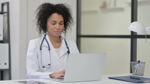 Smiling Woman Doctor Working on Laptop in Office