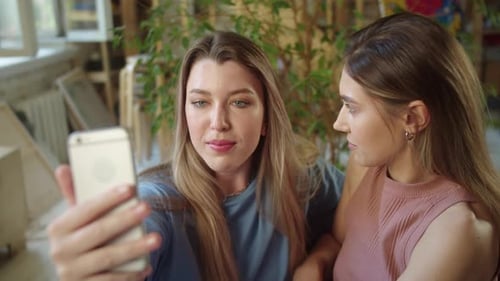 Two Young Women Take Selfie Together Indoors