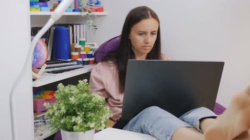 A Woman at Home with a Laptop in Her Hands Works or Studies Remotely