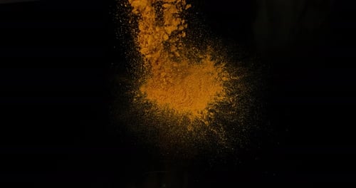 Cúrcuma, curcuma longa, polvo que cae sobre fondo negro, especia india, cámara lenta 4K