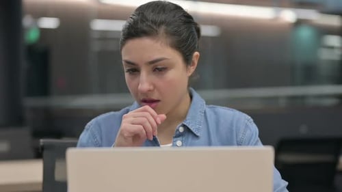 Nahaufnahme einer indischen Frau, die hustet, während sie einen Laptop benutzt