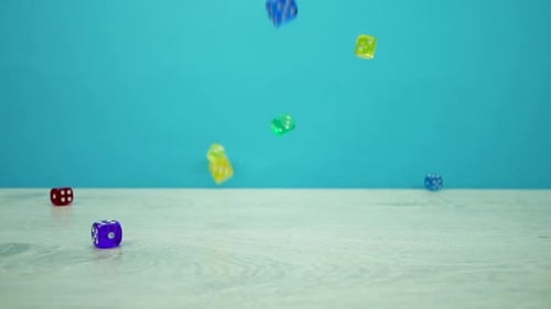 Foto a cámara lenta de dados multicolores cayendo sobre un fondo aguamarina