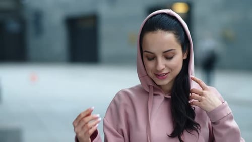 Fitness Woman Putting Hood Outdoor. Portrait of Smiling Woman in Pink Hoodie