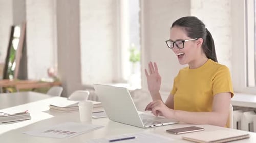 Smiling Woman Video Conferencing on Laptop at Desk