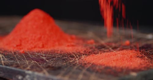 Powder Ground Red Chili Pepper Falls on the Table.