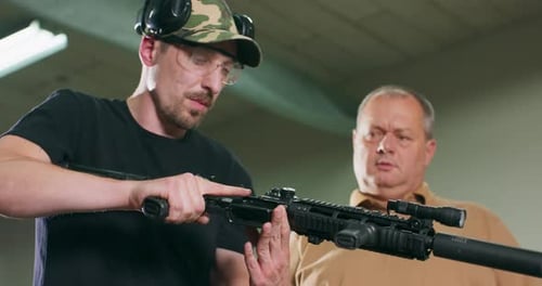 Men Examining a Tactical Rifle Indoors