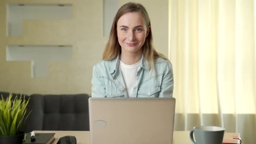 Smiling Woman Working on Laptop at Her Desk