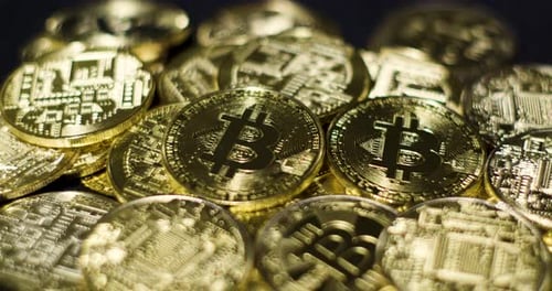 Echte goldene Münzen mit Bitcoin-Logo auf schwarzem Hintergrund