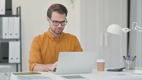 Young Man Working on Laptop in Office