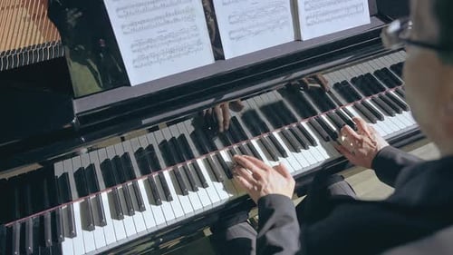 Man Plays Piano With Sheet Music in Home