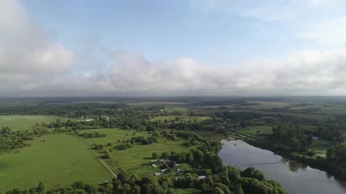 Smooth and Fast Flight Over the Lake and the Village. Plain Rural Landscape. Sunny Summer Day.