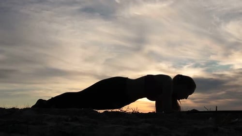 Woman Doing Plank Hip Twists on Beach at Sunset