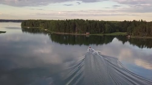 Motorboat Glides Across Lake Surrounded by Green Trees