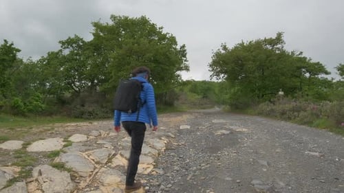 Young man with backpack hiking walking in the mountain road