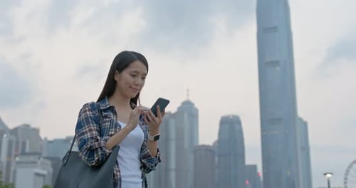 Une femme utilise un téléphone portable pour envoyer des SMS en ville