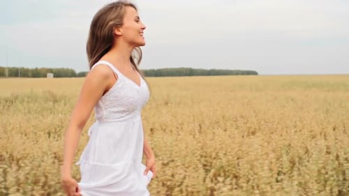Woman Running Through Wheat Field in White Dress