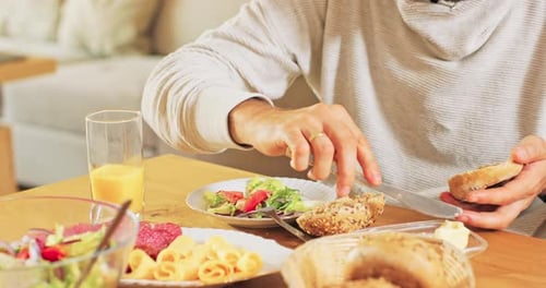 Person Makes Sandwich at Home with Salad and Cheese