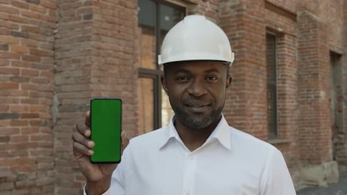Portrait of Builder Holding Phone with Green Screen Outside
