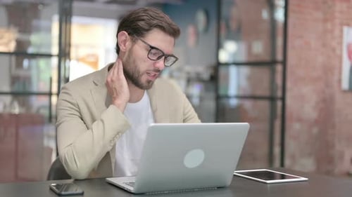 Young Adult Working on Laptop and Massaging Neck