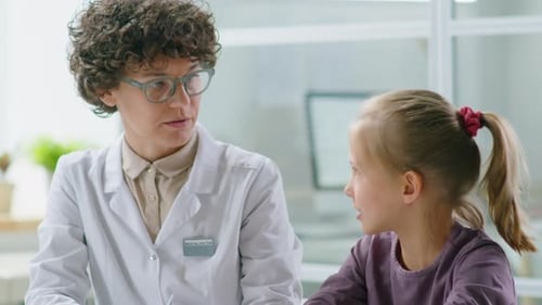 Female Pediatrician Working with Little Girl in Clinic