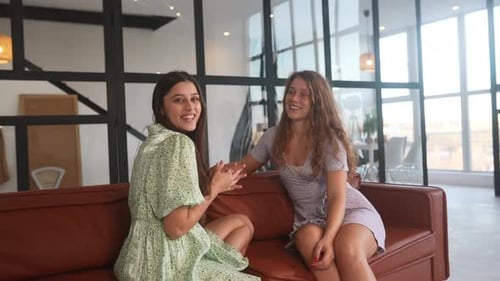 Des amies de jeunes filles souriantes partagent des ragots dans le salon
