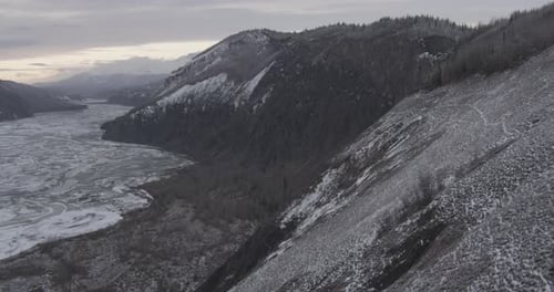 Lufthubschrauber schoss durch den Alaska-Canyon, durch den ein Fluss fließt, karger Wald, Berg