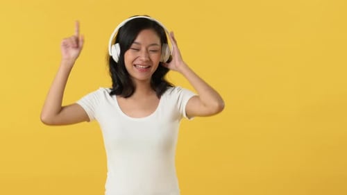 Woman Dancing with Headphones on Yellow Background