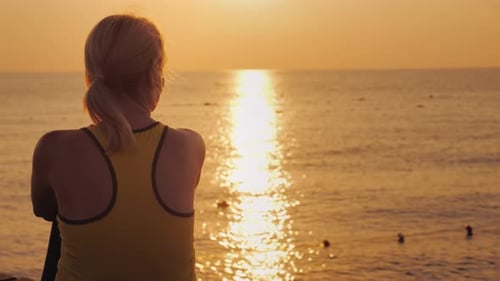 Fitness Woman Admiring the Sunrise Over the Sea