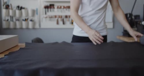 Young Leather Worker Examining Large Leather Piece Table Workshop
