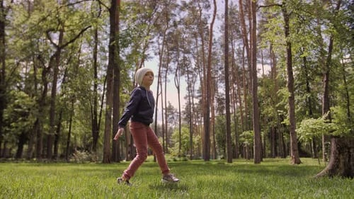 Carefree Girl Dancing and Spinning on a Green Meadow in the Park Late Afternoon