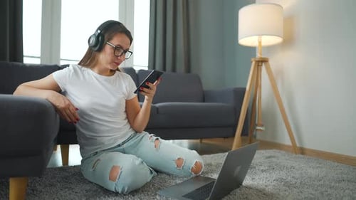 Woman Using Phone and Laptop at Home