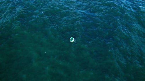 Images aériennes de Drone 4k faisant le tour d'une bouée qui bouge dans les vagues près de la côte