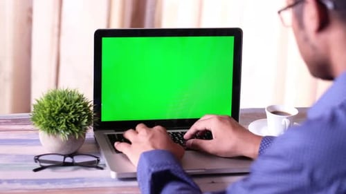 Vista posterior del empresario que trabaja en una computadora portátil con pantalla verde