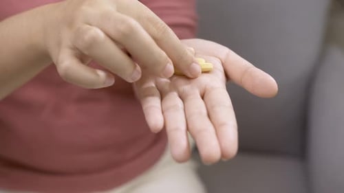 Hand Holding Yellow Pills for Health and Wellness
