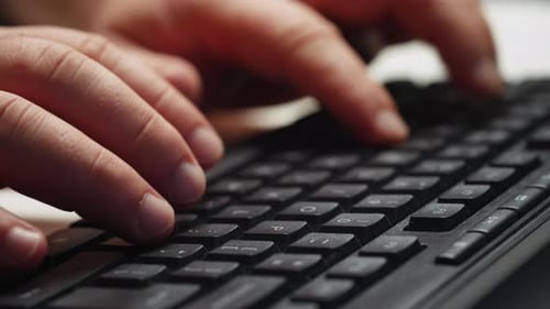 Manos de hombre escribiendo en el teclado del ordenador.